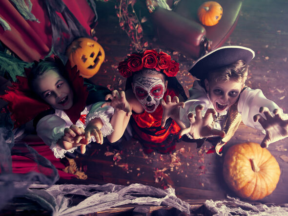 Drei Kinder feiern Halloween auf einer Party im Kostüm.