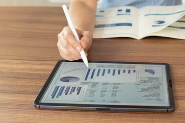 Eine Person arbeitet mit Laptop und Tablet.