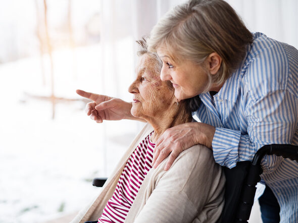 Eine Frau zeigt einer Seniorin etwas