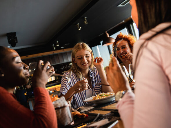 Eine Gruppe junger Frauen essen und reden im Restaurant