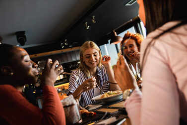 Eine Gruppe junger Frauen essen und reden im Restaurant