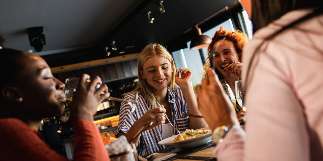 Eine Gruppe junger Frauen essen und reden im Restaurant