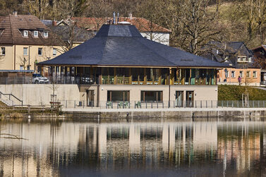 Das Haus am See bei Tag. Das Haus spiegelt sich im See.