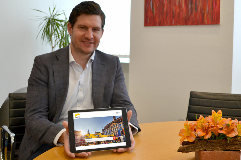OB Dominik Sauerteig hält ein Tablet, das die neue Website zeigt.