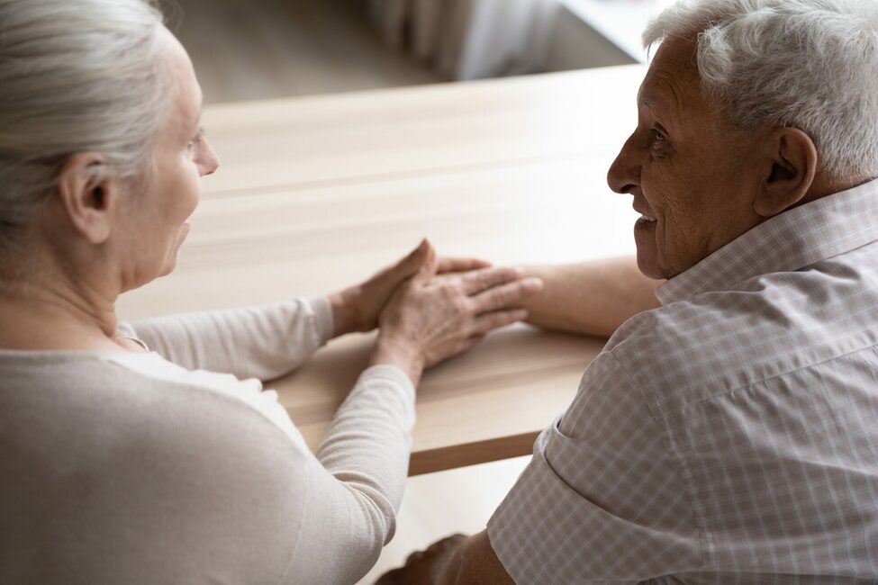 Eine ältere Frau reicht ihre Hand einem älteren Mann.