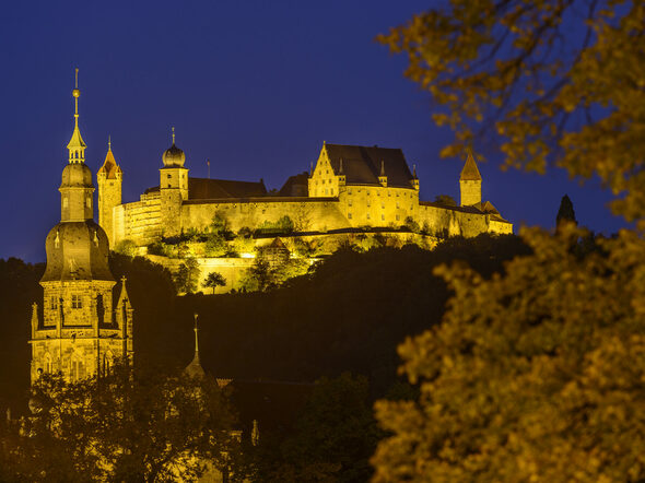 Veste Coburg und Morizkirche sind nachts beleuchtet.