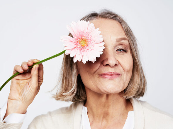 Cheerful,Elegant,Elderly,Woman,Holding,A,Flower,Near,The,Face