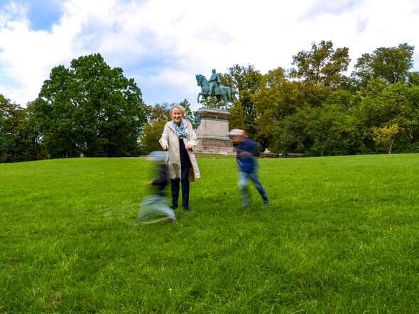Eine Leihoma spielt mit zwei Jungs im Hofgarten.