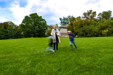Eine Leihoma spielt mit zwei Jungs im Hofgarten.