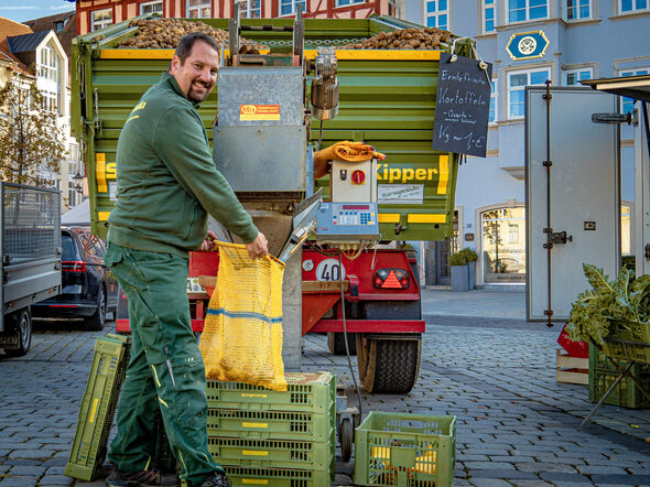 Ein Händler füllt Kartoffeln von seinem Traktor in einen Kartoffelsack.