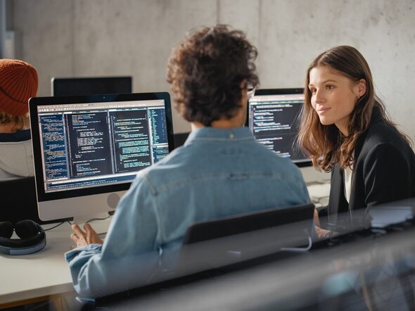 Ein junger Mann und eine junge Frau sitzen vor einem Computer