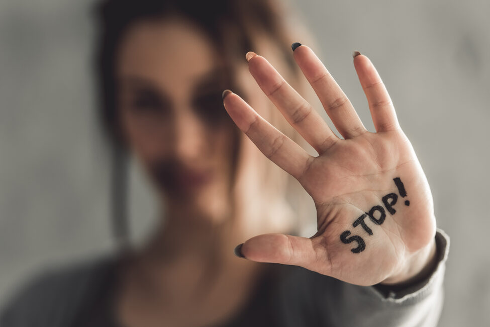 Eine junge Frau hält eine offene Handfläche mit der Aufschrift "Stop!" in die Kamera