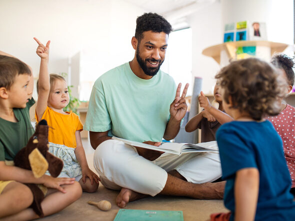 Ein Erzieher sitzt in einer Gruppe von Kindern