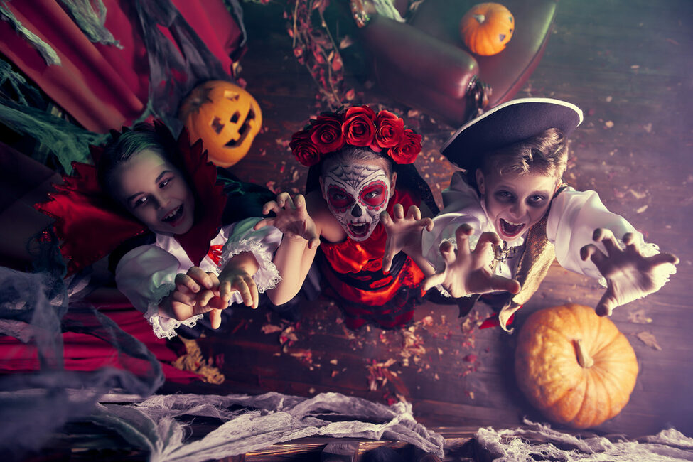 Drei Kinder feiern Halloween auf einer Party im Kostüm.