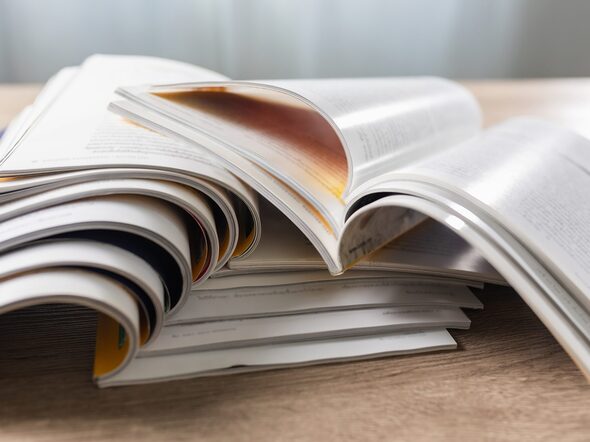 Mehrere aufgeblätterte Zeitschriften auf einem Stapel.