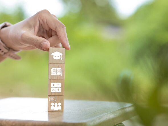 Eine Hand, die vier Holzwürfel aufeinander stapelt.