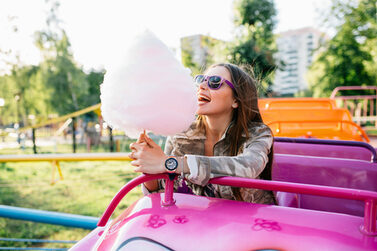 Ein glückliches Mädchen isst ihre Zuckerwatte auf der Achterbahn.