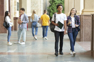 Gut gelaunte Studierende laufen auf dem Campus